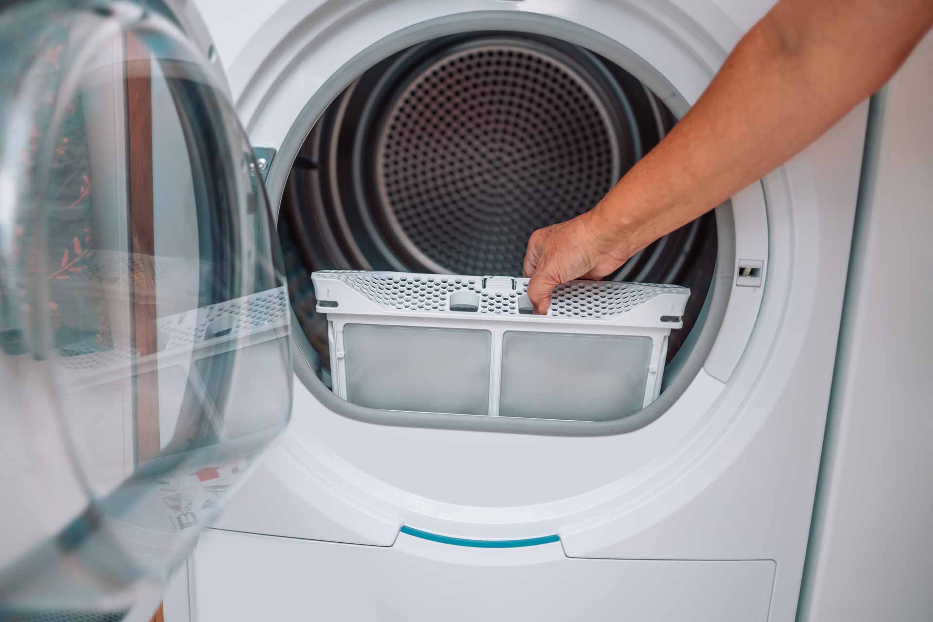 Hand reaching in to frame to pull lint trap out of a dryer